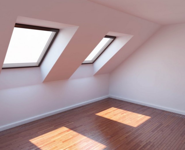 An image of a modern loft conversion with laminate flooring and two windows.