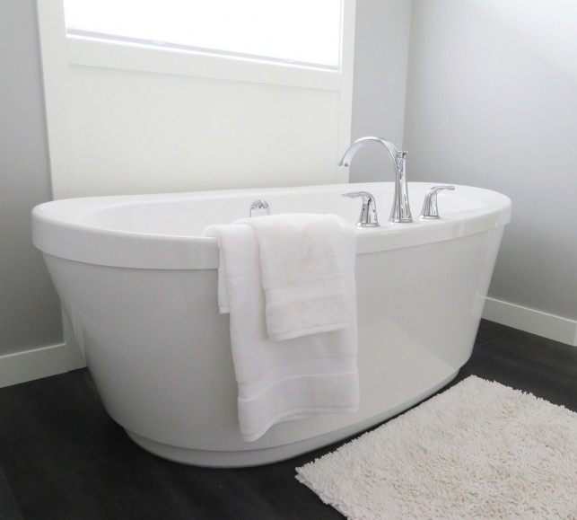 An image of a white-standing bath tub situated in a bathroom.