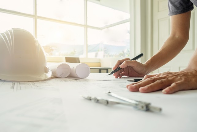 An image of the hands of an engineer, working on a blueprint, construction concept.