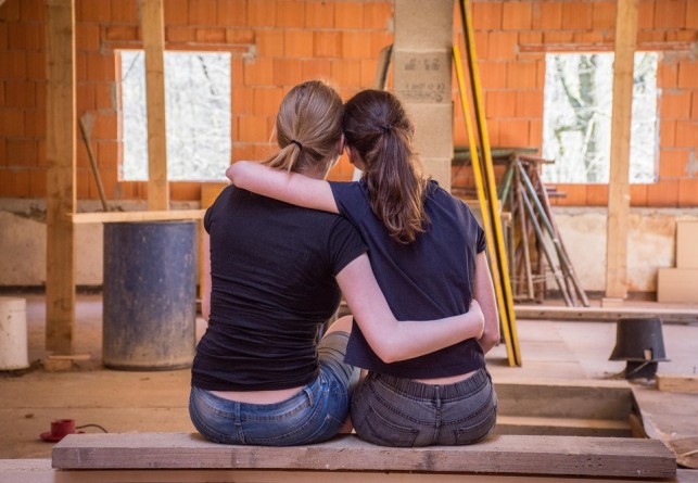 An image of two women sitting down in a house that is undergoing renovation.